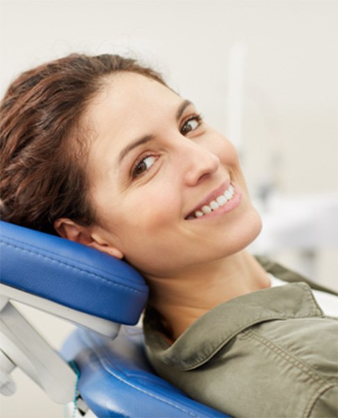 Female periodontal patient leaning back in chair and smiling