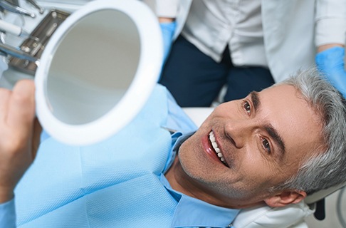 A middle-aged man admiring his new smile while at the dentist’s office in Dallas