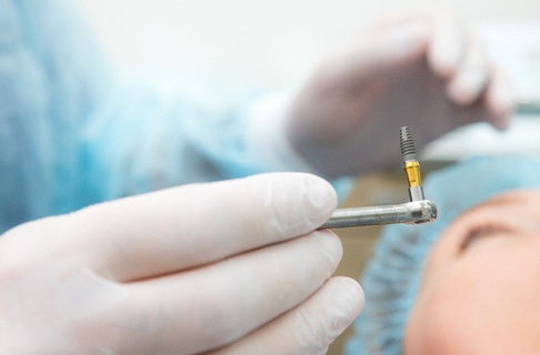 Periodontist preparing to place dental implant in patient’s mouth