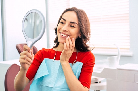 Dental patient using mirror to admire her new restorations