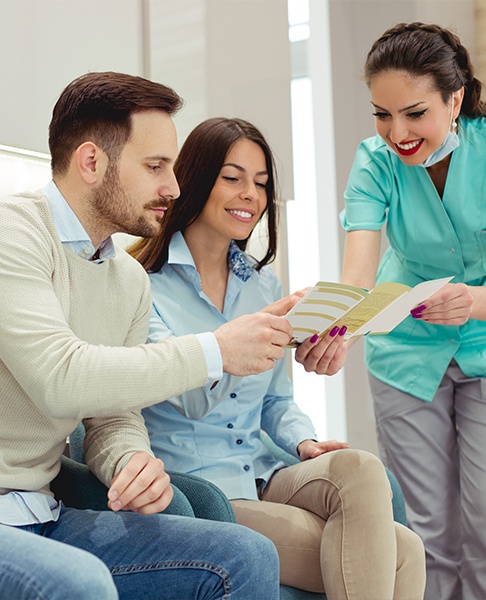 Man and woman discussing dental implant costs with periodontal team member