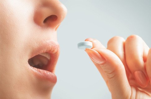 Holding glass of water and pills for oral conscious sedation in Dallas, TX