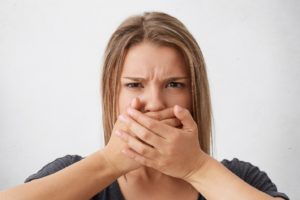 Young woman covering mouth, concerned about gum overgrowth