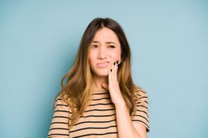 Young woman clutching her jaw in pain.