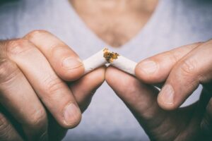 Person breaking cigarette in half. 
